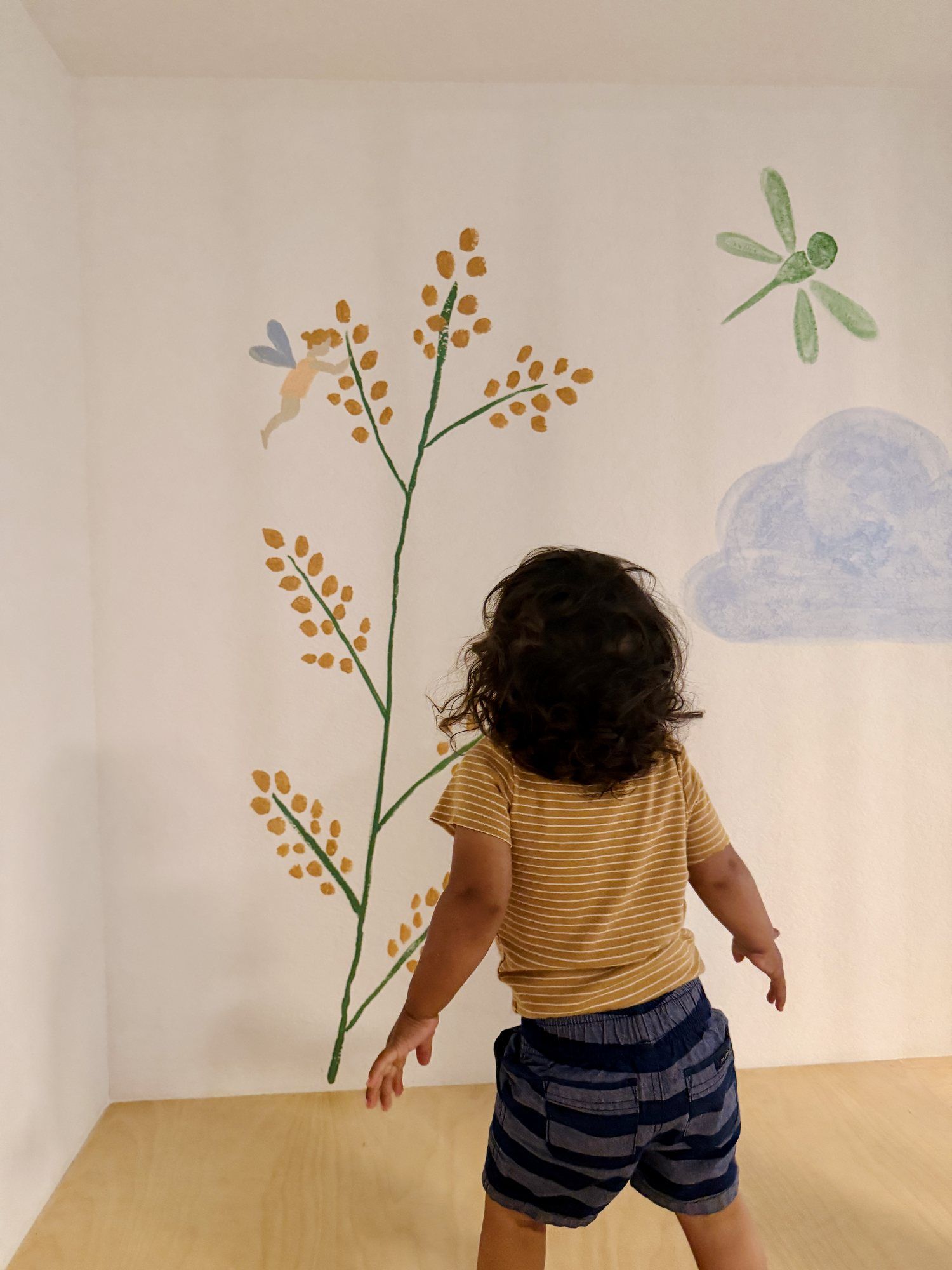 A child looking up at the dragonfly on the mural