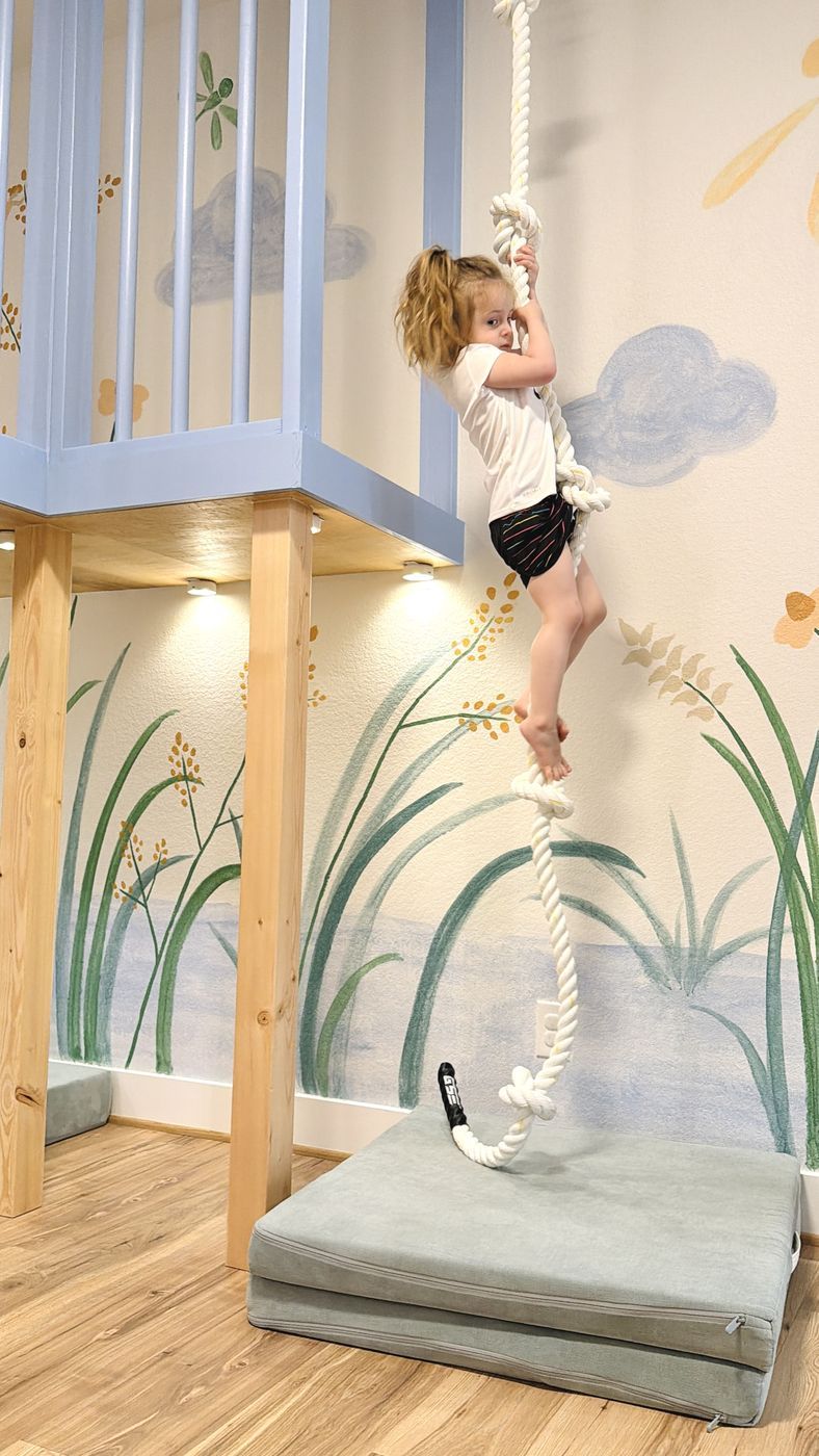 Child climbing rope beside blue loft