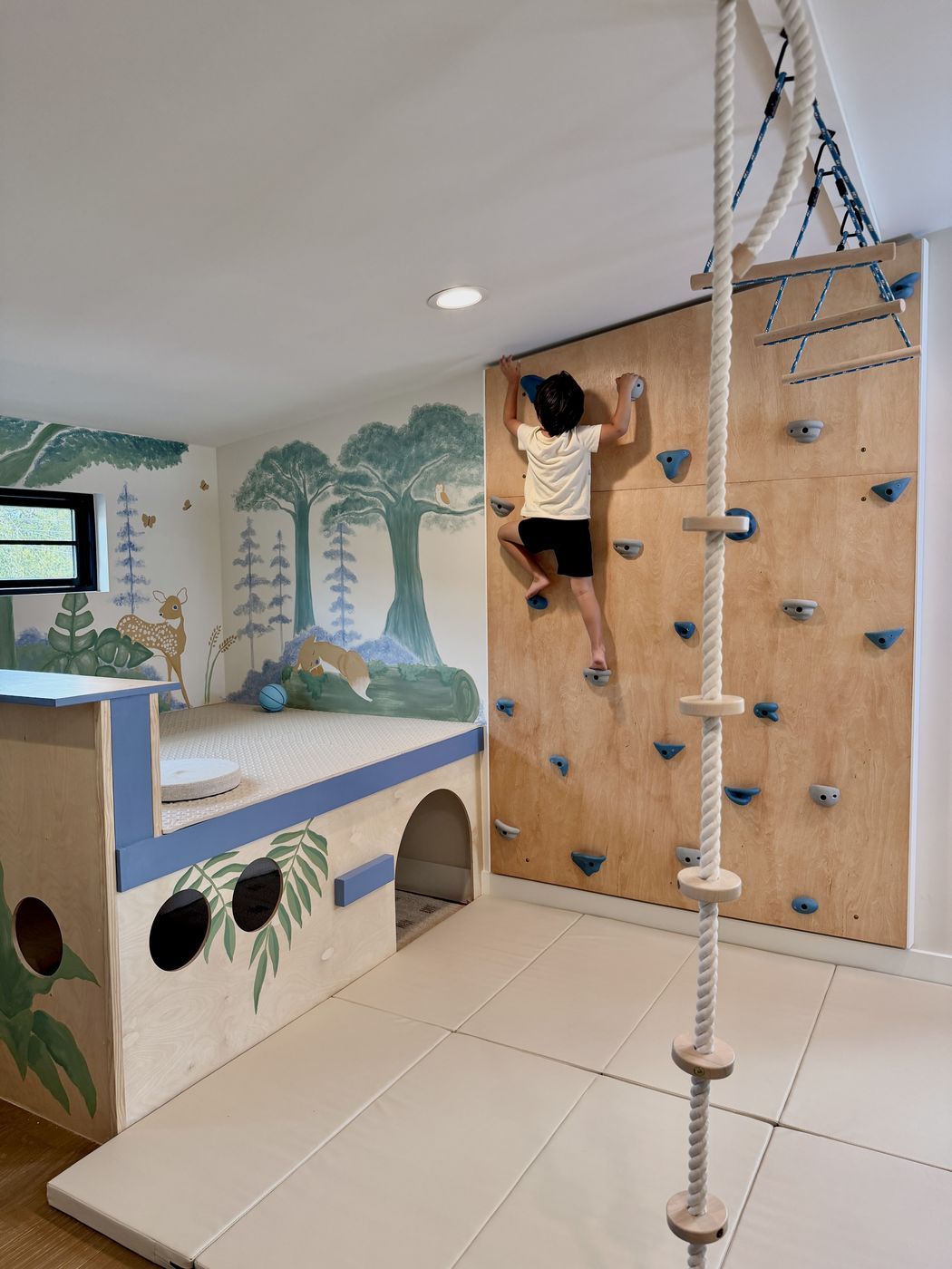 Child climbing wall beside rope