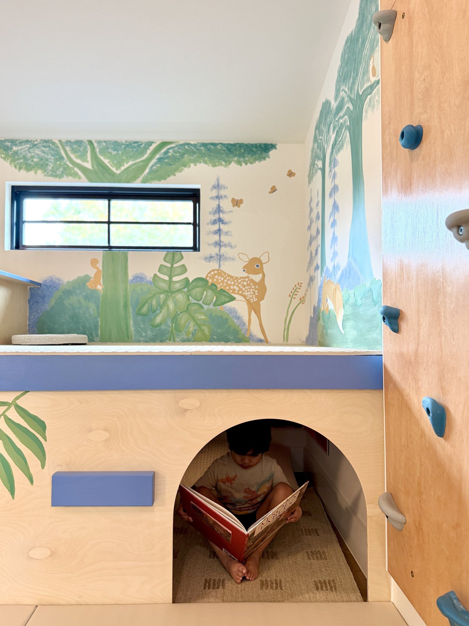 A child reading in the arched hideaway under the platform