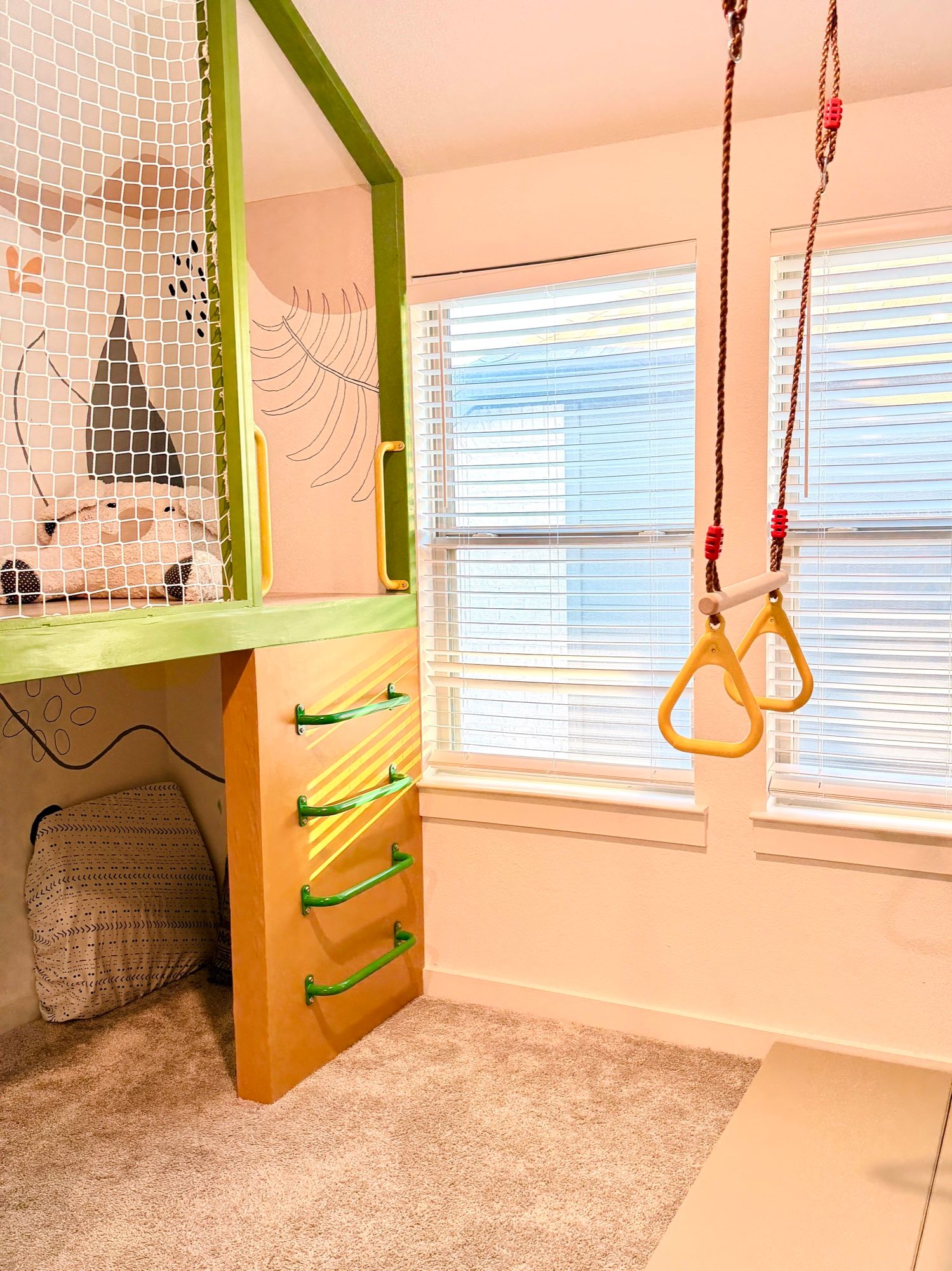 Gym rings by the window, beside the playhouse and its green rungs