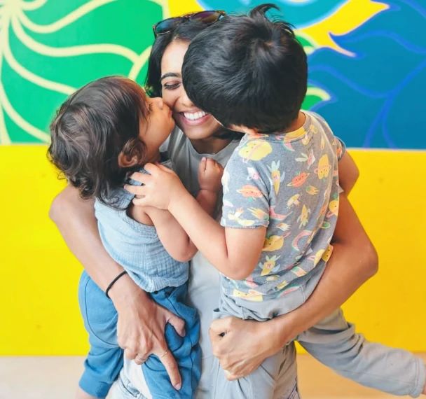 Sphurti laughing as her two young sons hug and kiss her