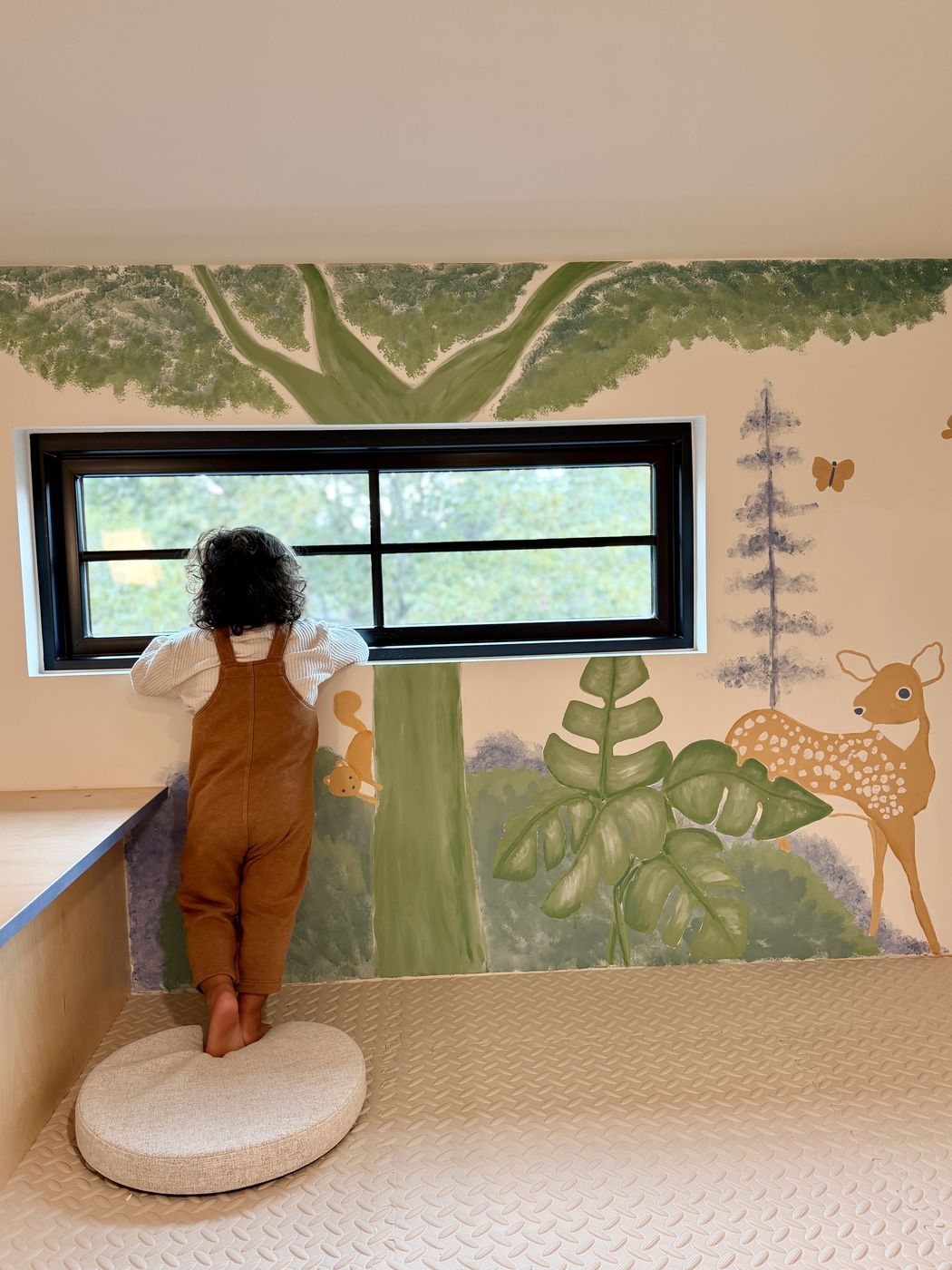 Toddler at window forest mural