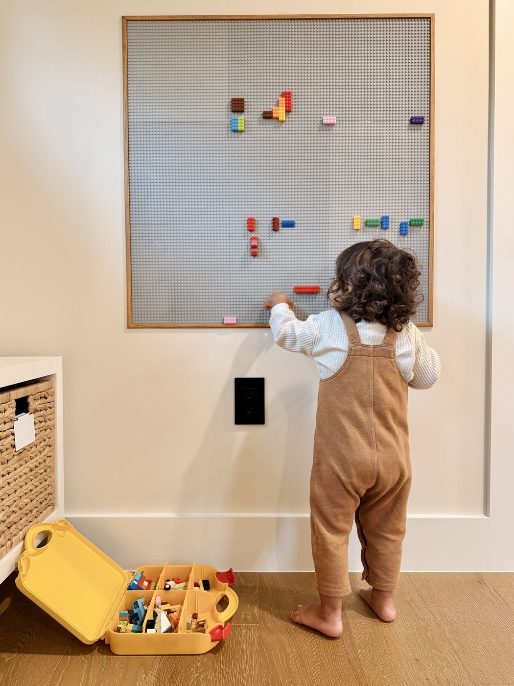 Toddler building on lego wall