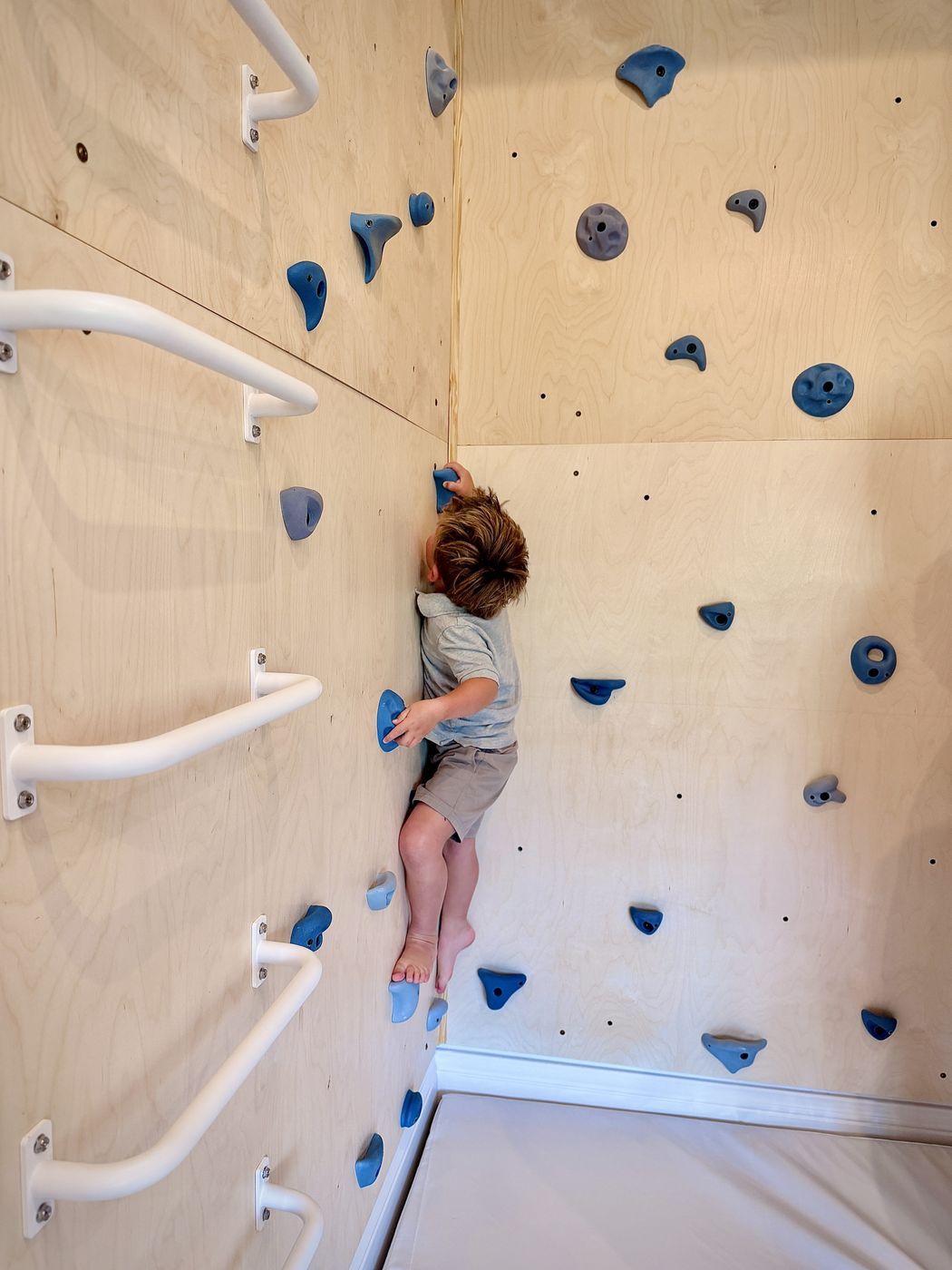 Toddler climbing plywood rock wall