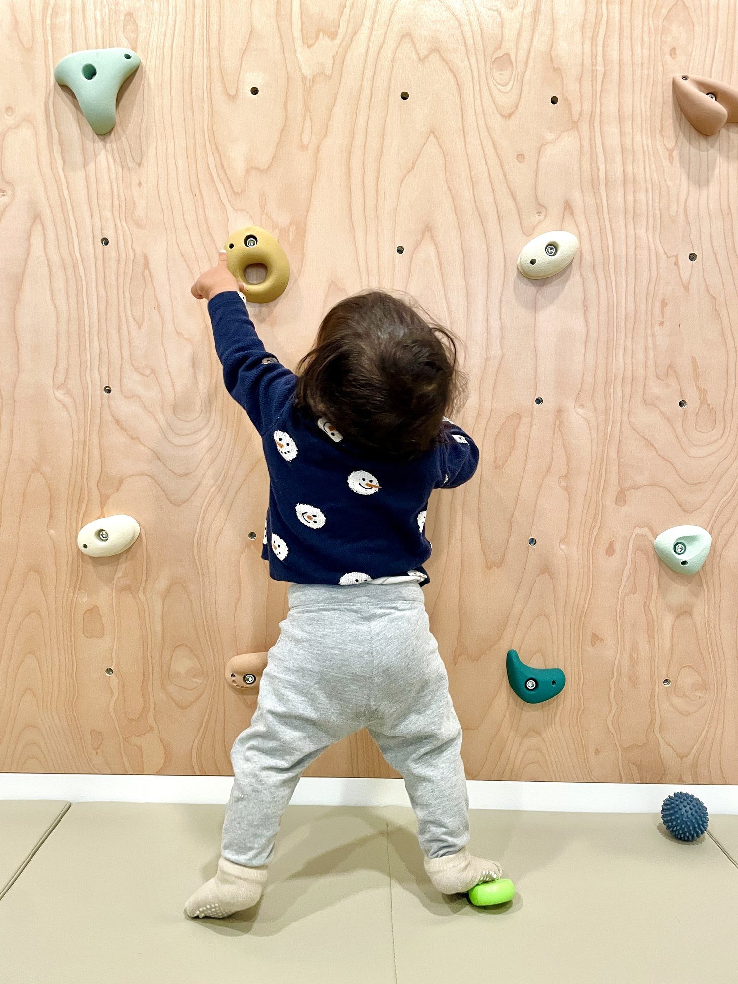A toddler reaching for the climbing holds
