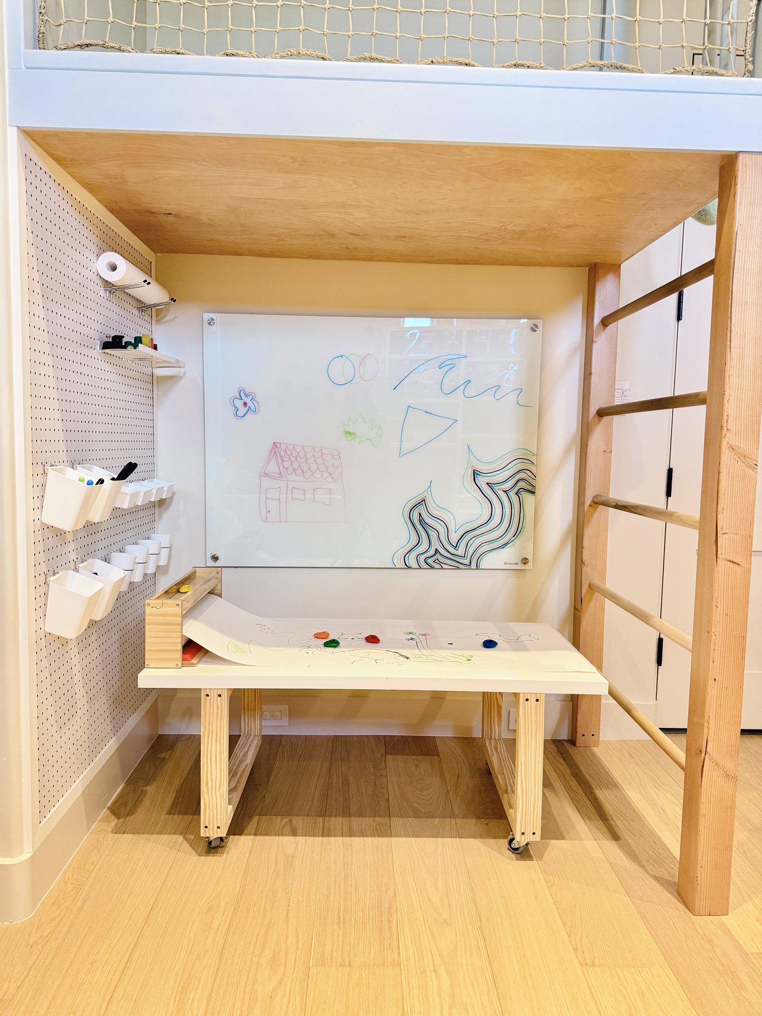 The art station under the loft, with pegboard storage and a dry-erase wall